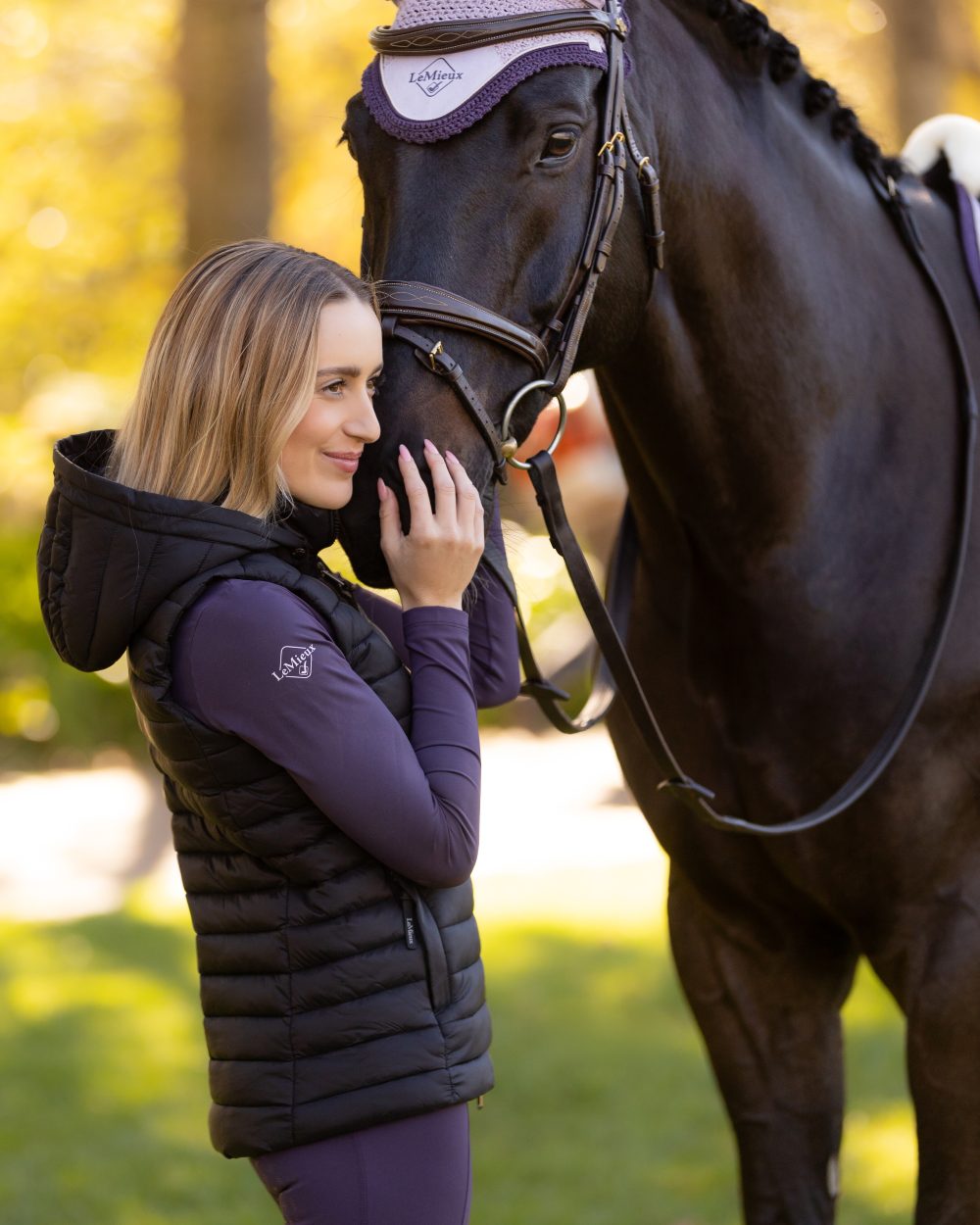 Black coloured LeMieux Womens Rose Hooded Puffer Gilet on blurry background