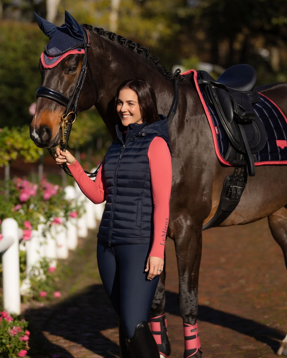 Navy coloured LeMieux Womens Rose Hooded Puffer Gilet on garden background