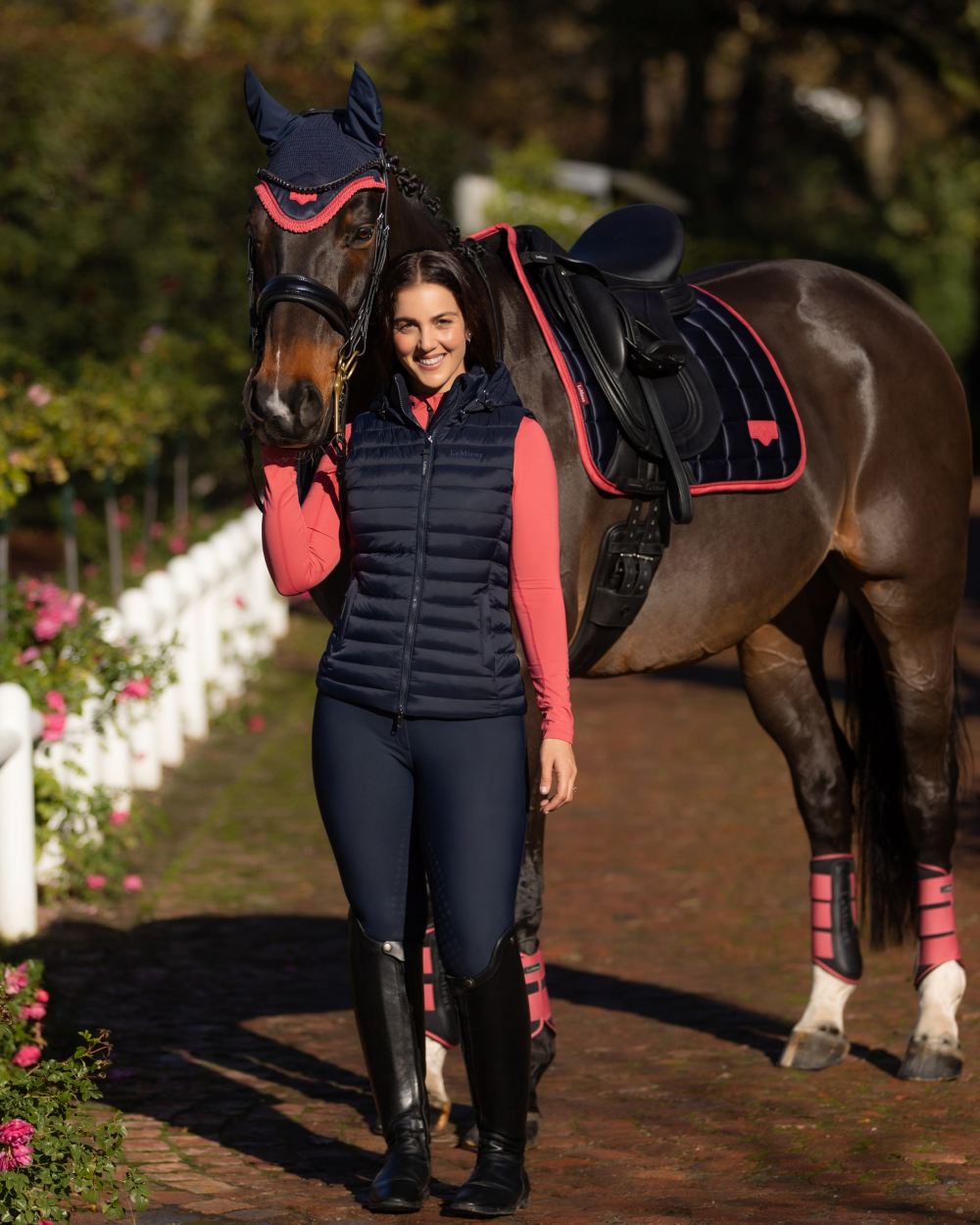 Navy coloured LeMieux Womens Rose Hooded Puffer Gilet on garden background