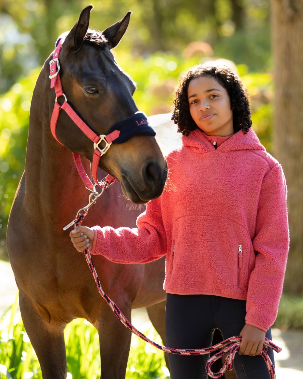 Cranberry coloured LeMieux Young Rider Avalon Hoodie on tree background