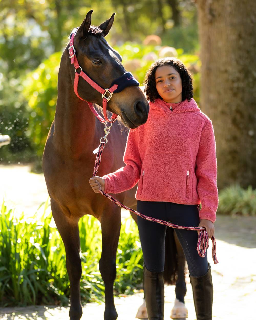 Cranberry coloured LeMieux Young Rider Avalon Hoodie on tree background