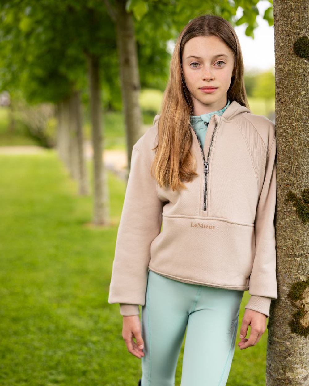 Almond coloured LeMieux Young Rider Harriet Pop Over Hoodie on lawn background