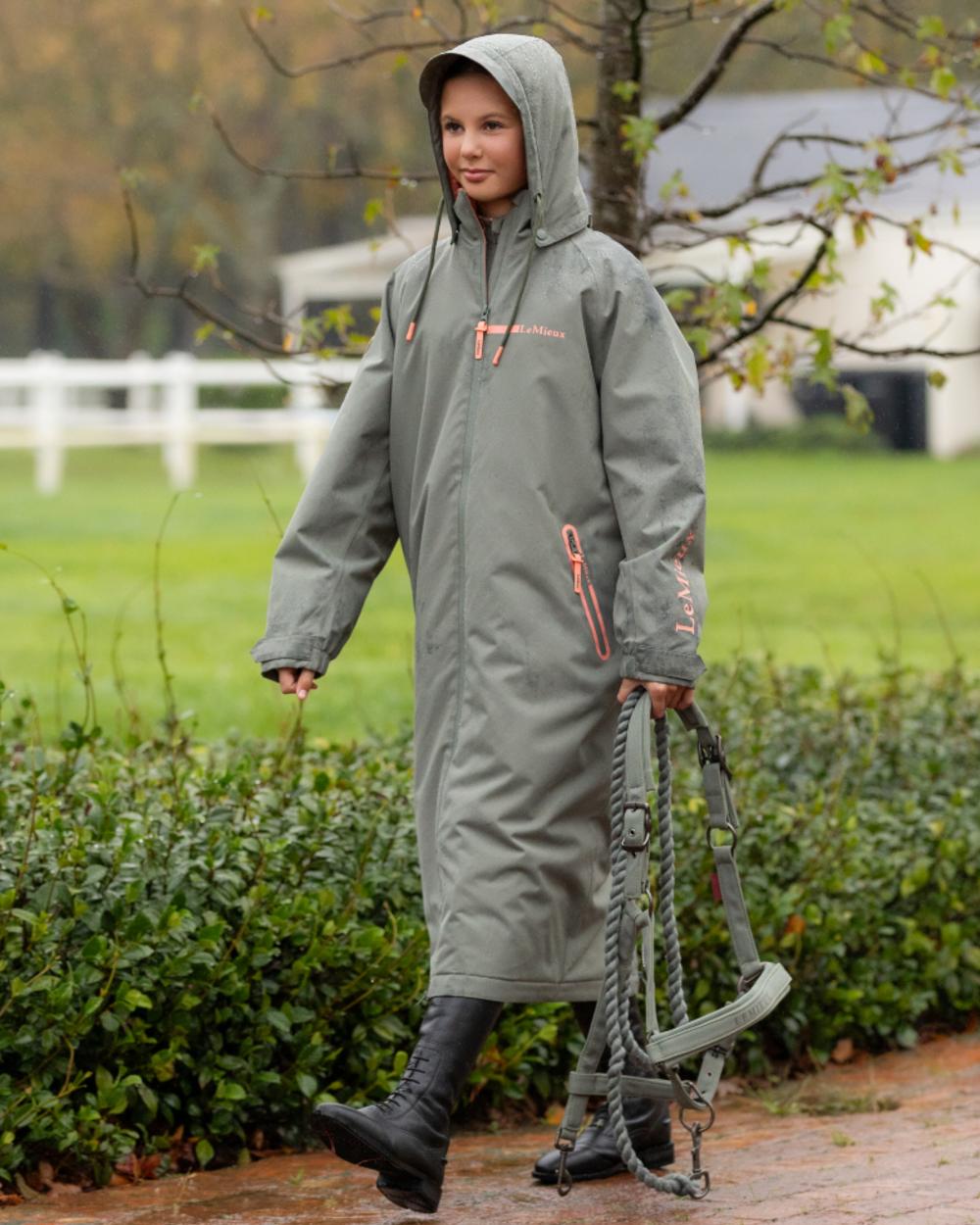 Rosemary coloured LeMieux Young Rider HydroShield Robe Long Coat on garden background