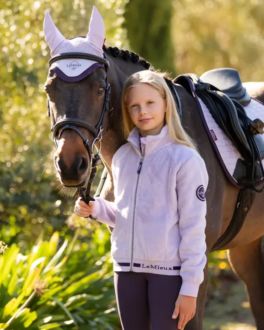 Lilac Coloured LeMieux Young Rider Libby Fleece Jacket On A Leafy Background