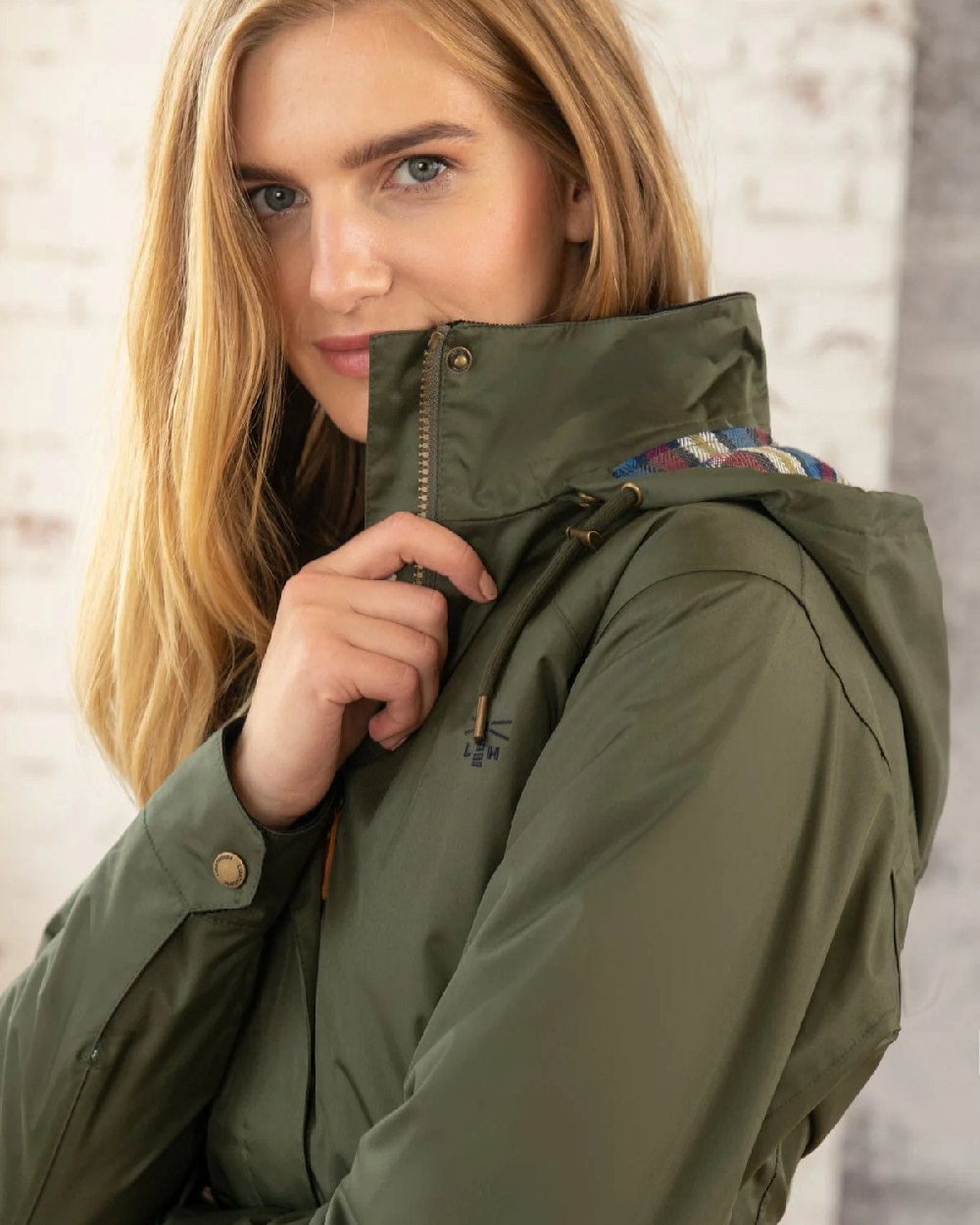 Forest coloured Lighthouse Kendal Waterproof Coat on wall background