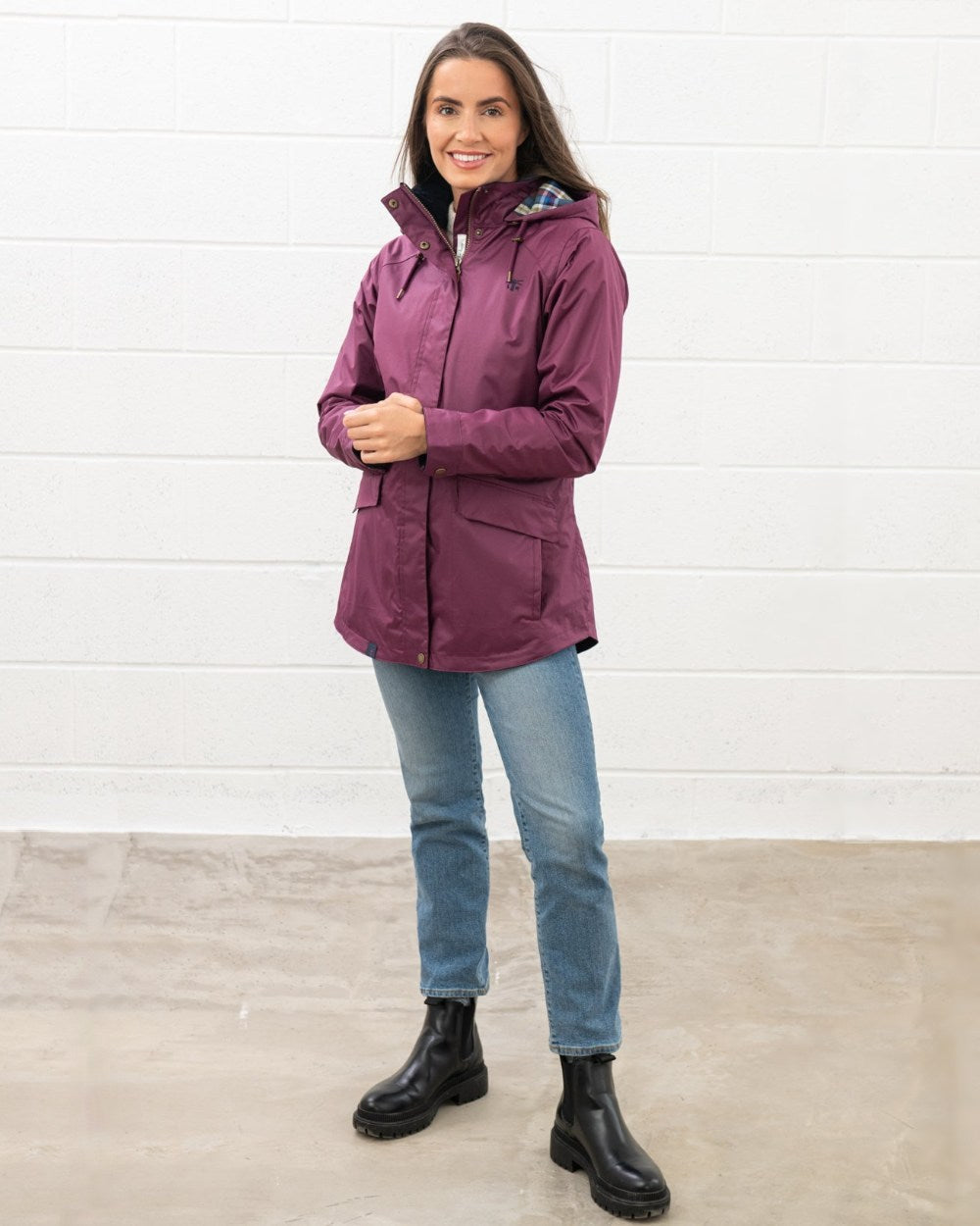 Plum coloured Lighthouse Kendal Waterproof Coat on wall background