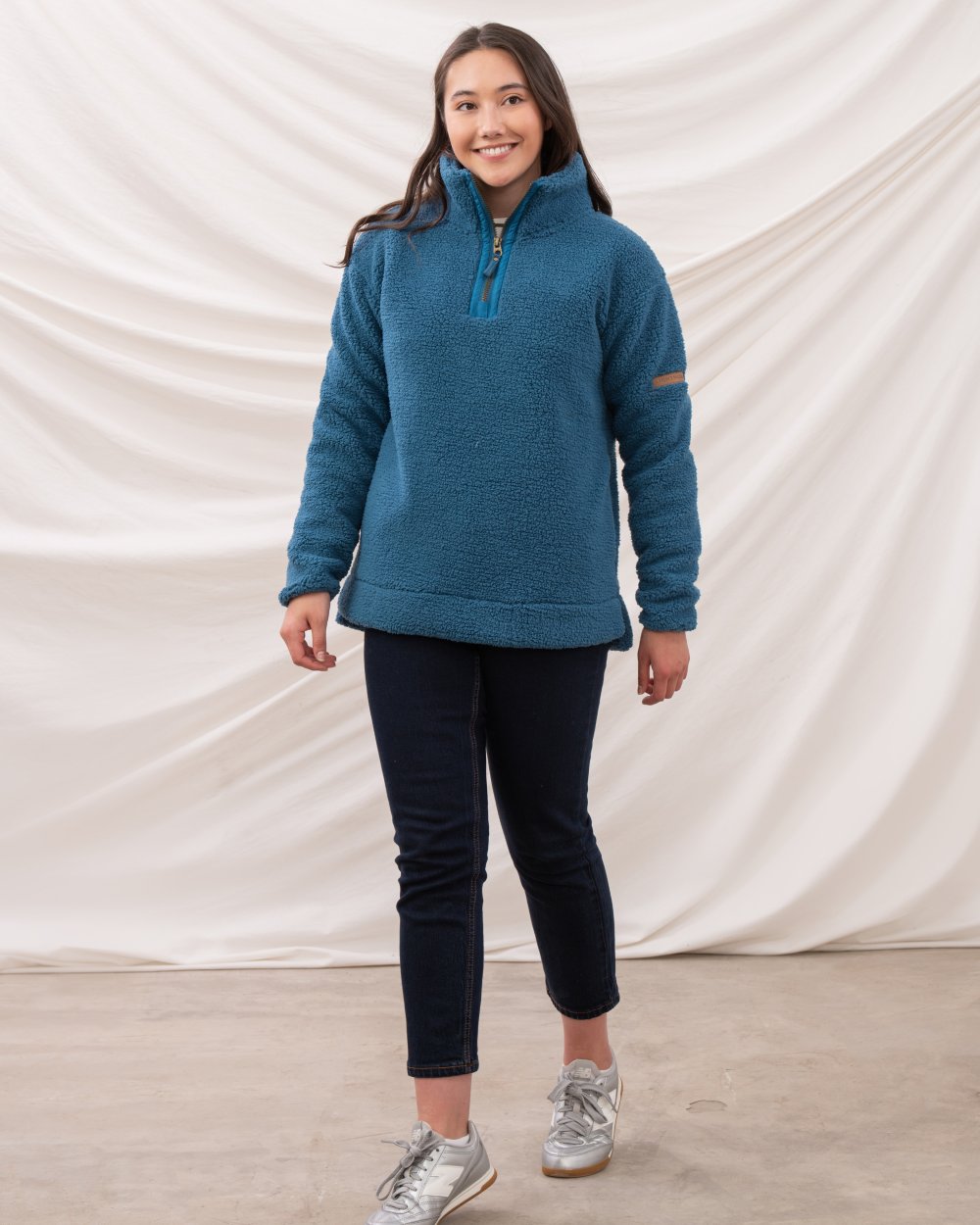 Teal coloured Lighthouse Ladies Coast Half Zip Fleece Sweater on curtain background