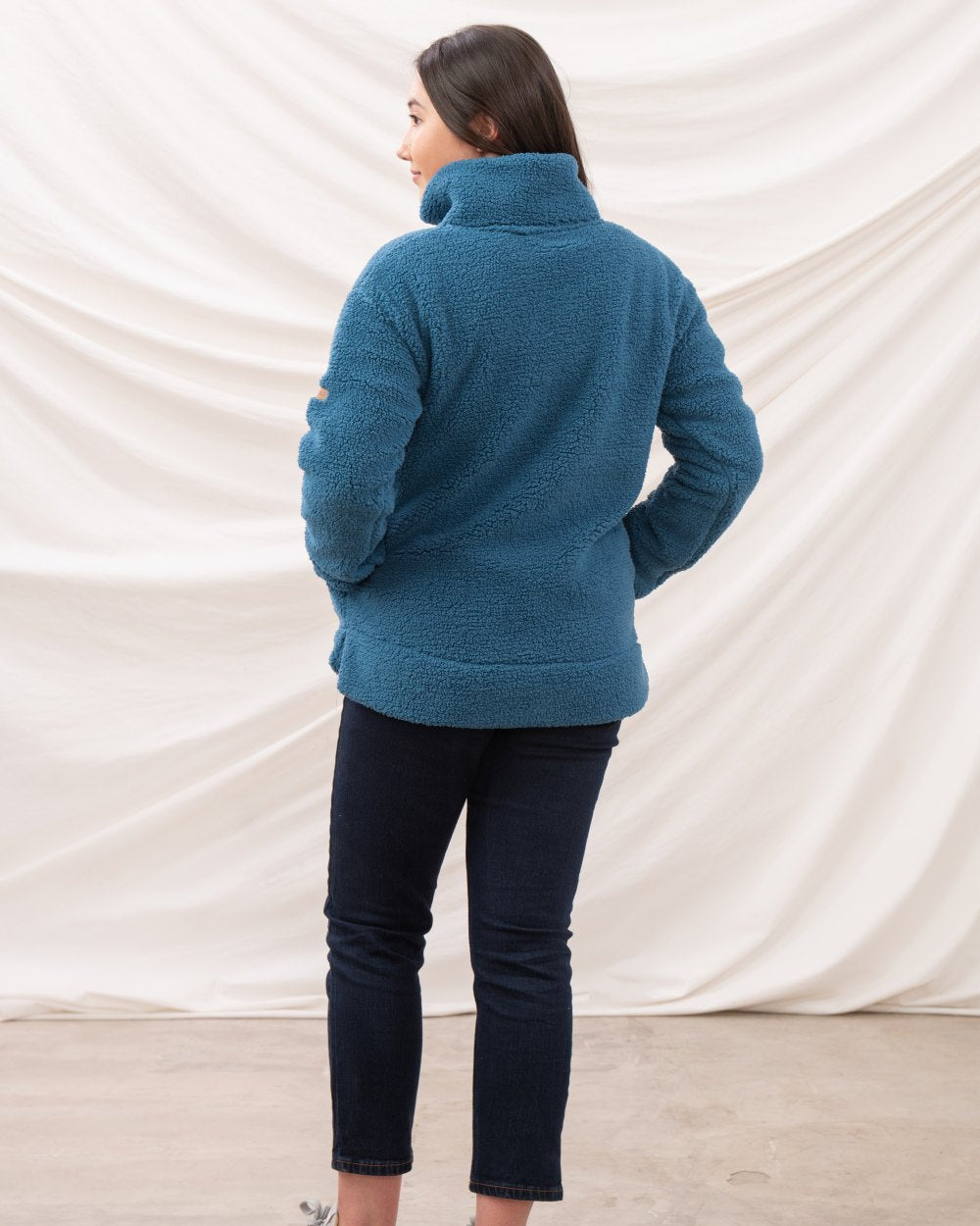 Teal coloured Lighthouse Ladies Coast Half Zip Fleece Sweater on curtain background