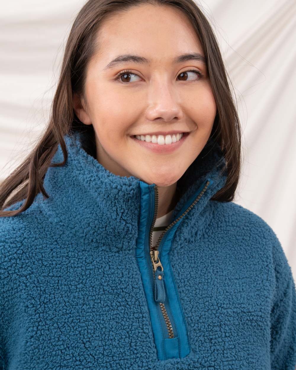 Teal coloured Lighthouse Ladies Coast Half Zip Fleece Sweater on curtain background