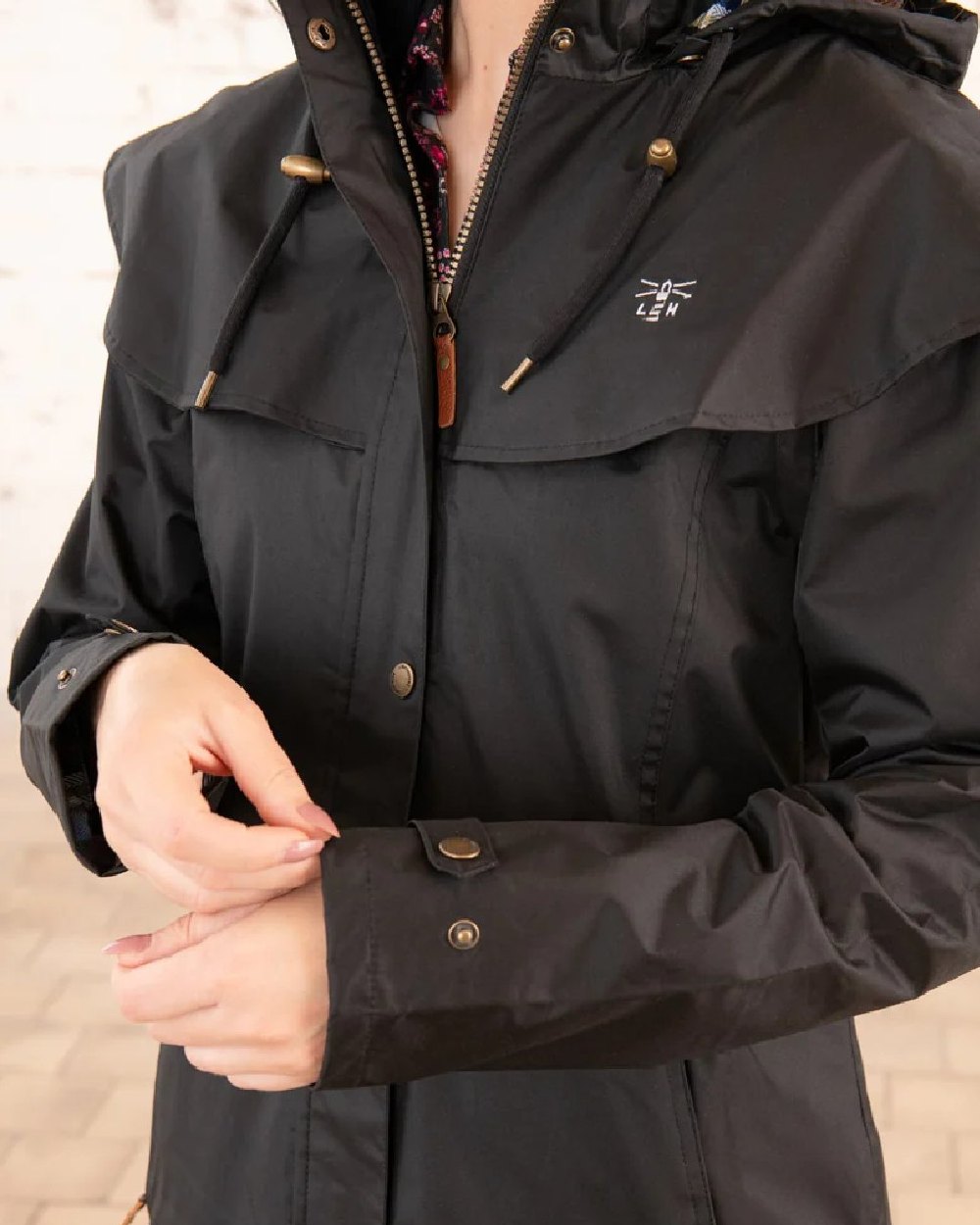 Black coloured Lighthouse Outback Full Length Ladies Waterproof Raincoat on wall background