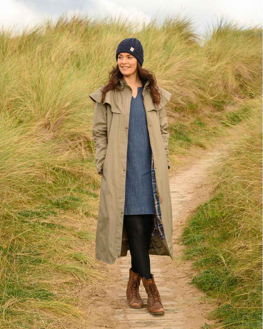 Fawn coloured Lighthouse Outback Full Length Ladies Waterproof Raincoat on grassy background