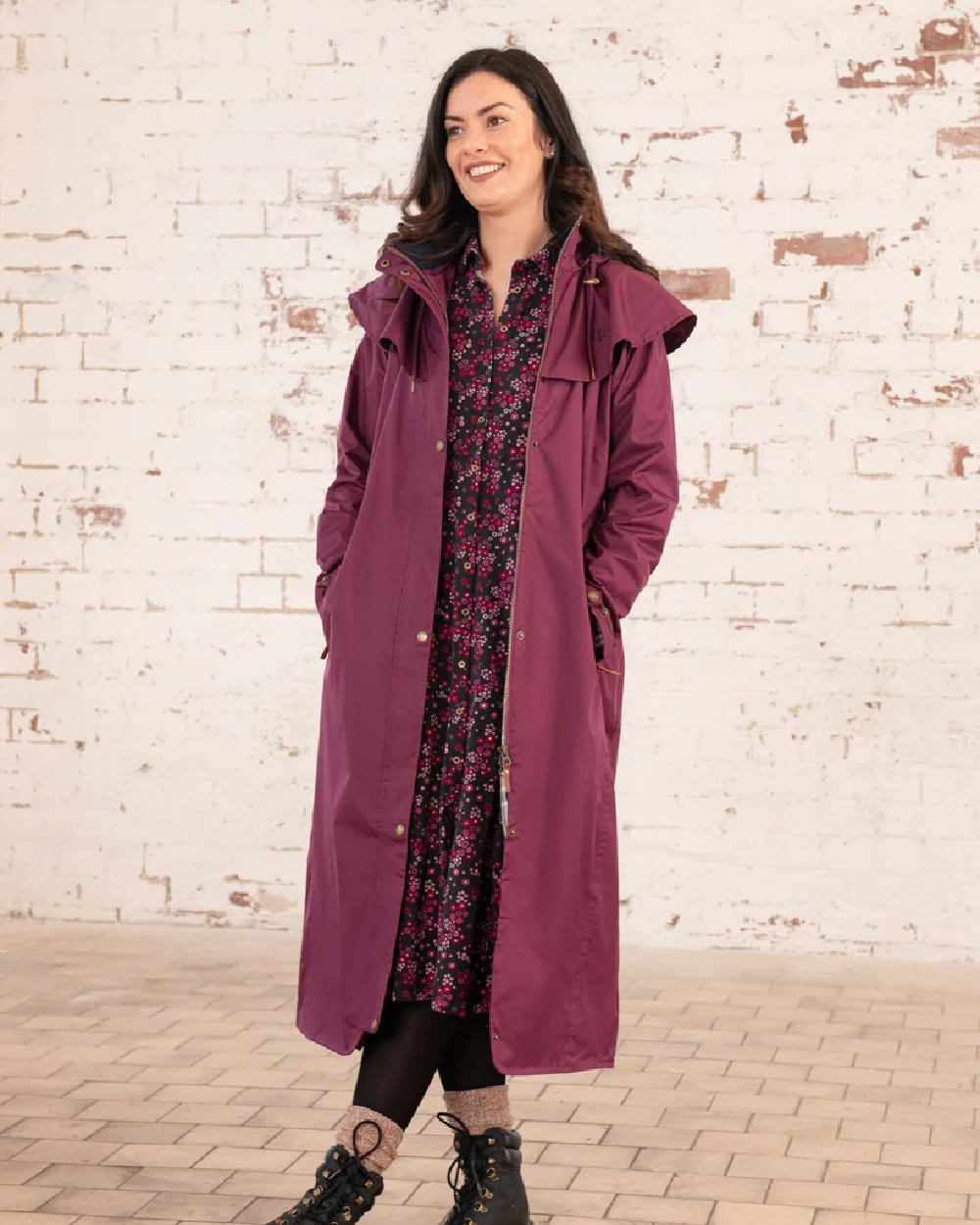 Plum coloured Lighthouse Outback Full Length Ladies Waterproof Raincoat on wall background