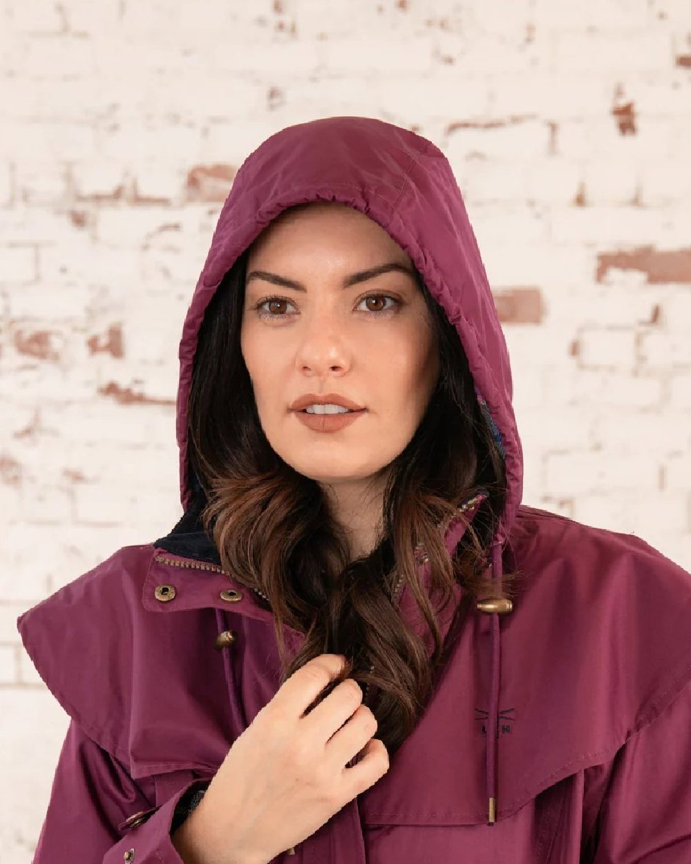 Plum coloured Lighthouse Outback Full Length Ladies Waterproof Raincoat on wall background