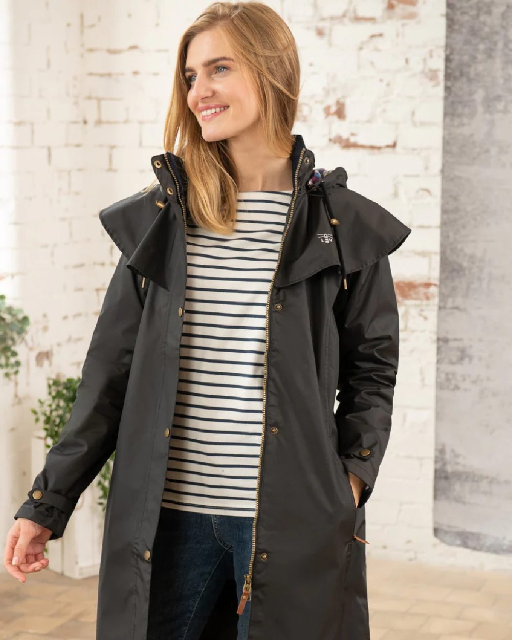 Black coloured Lighthouse Outrider 3/4 Length Ladies Waterproof Raincoat on wall background