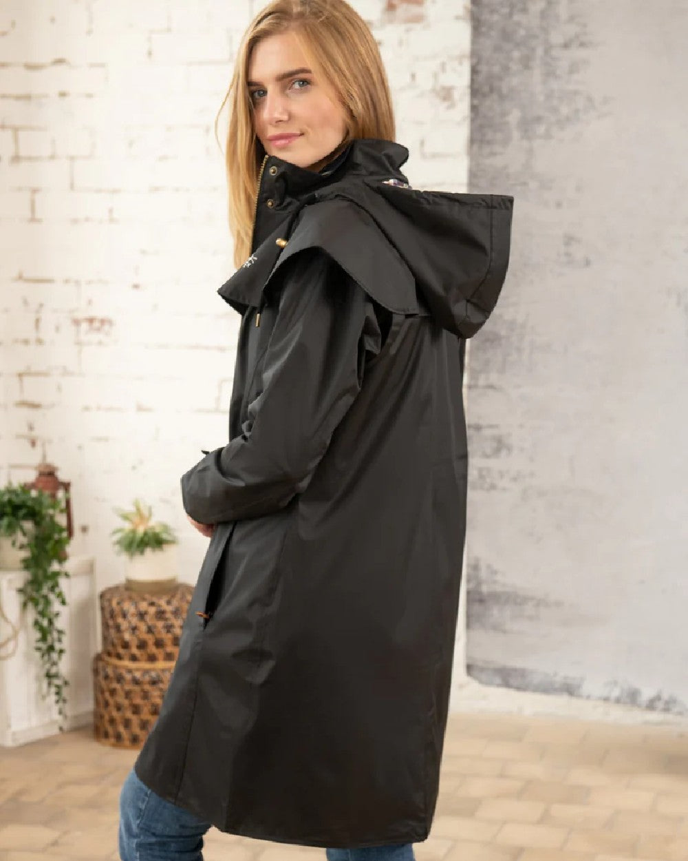 Black coloured Lighthouse Outrider 3/4 Length Ladies Waterproof Raincoat on wall background