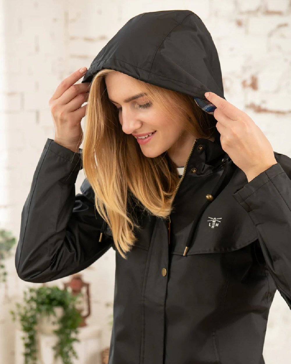 Black coloured Lighthouse Outrider 3/4 Length Ladies Waterproof Raincoat on wall background