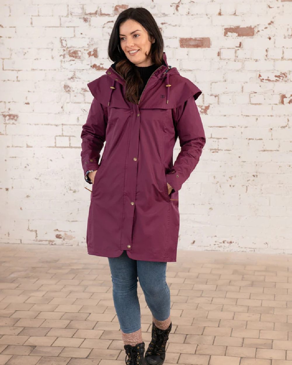 Plum coloured Lighthouse Outrider 3/4 Length Ladies Waterproof Raincoat on wall background