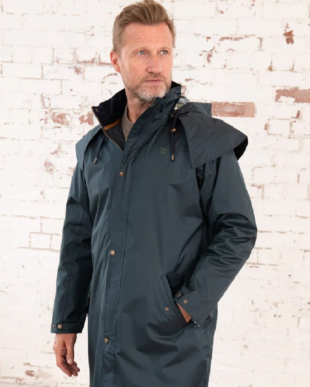 Navy coloured Lighthouse Stockman Long Waterproof Coat on wall background