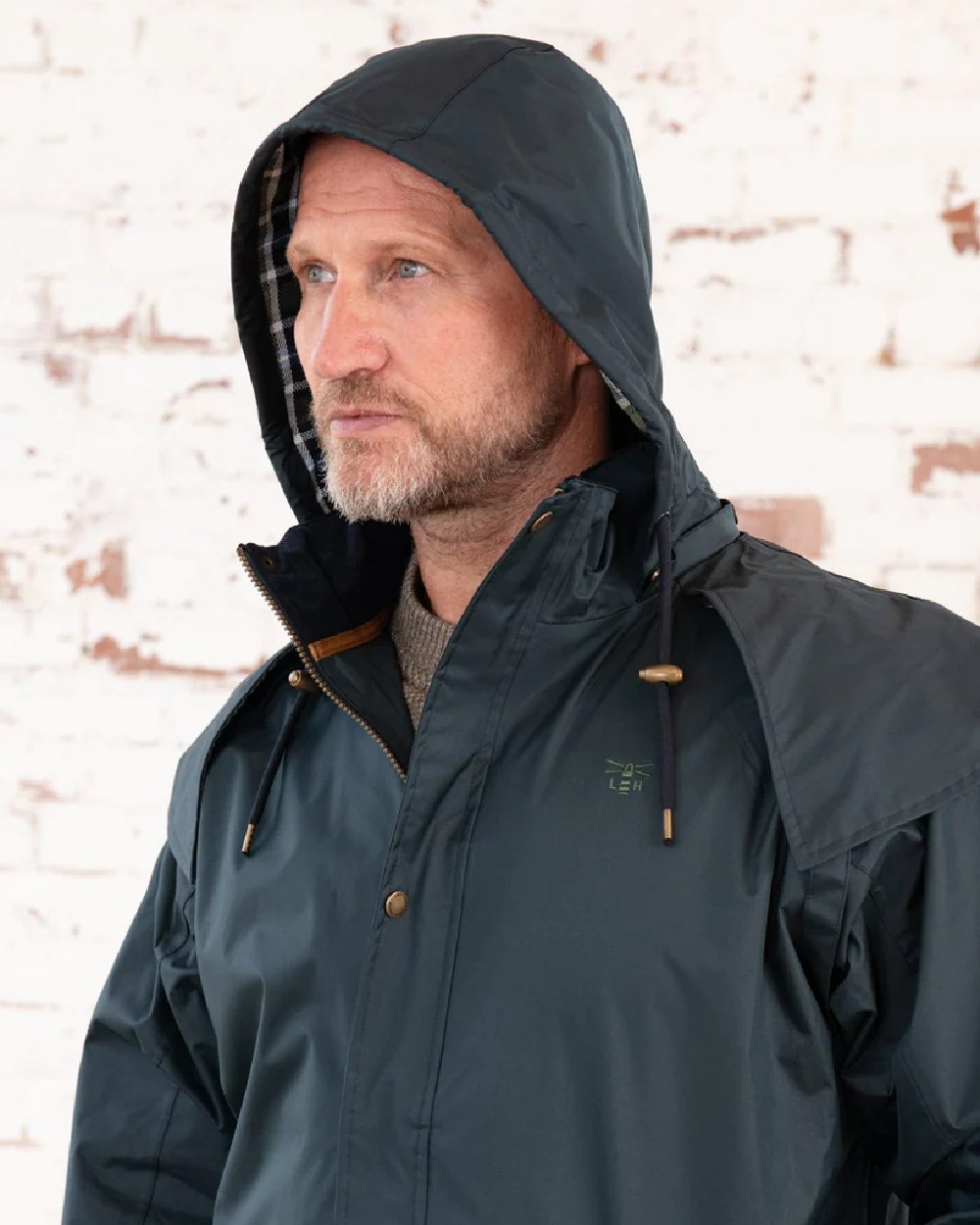 Navy coloured Lighthouse Stockman Long Waterproof Coat on wall background