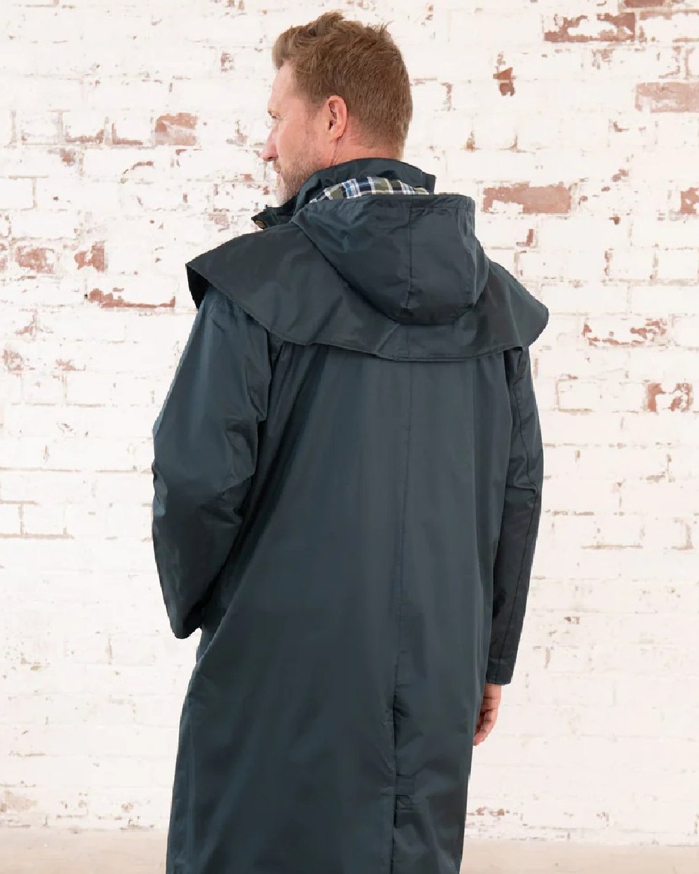 Navy coloured Lighthouse Stockman Long Waterproof Coat on wall background