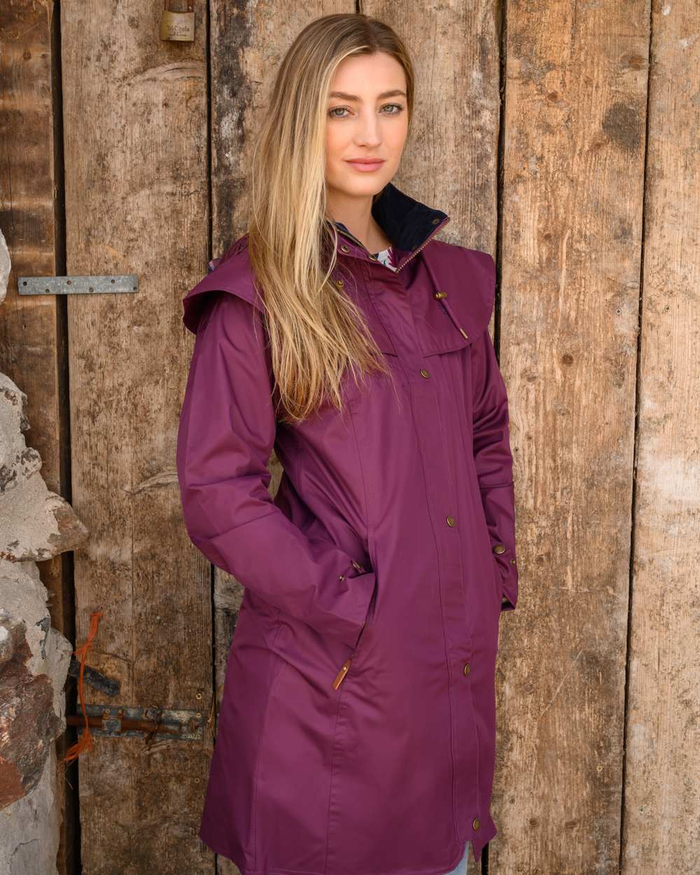 Plum coloured Lighthouse Outrider 3/4 Length Ladies Waterproof Raincoat on Wooded Door background 