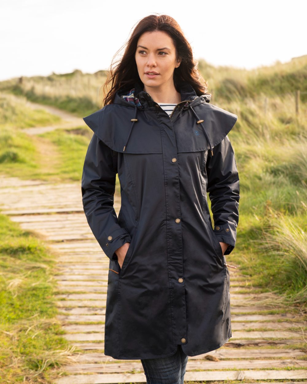 Nightshade coloured Lighthouse Outrider 3/4 Length Ladies Waterproof Raincoat Board Walk background 