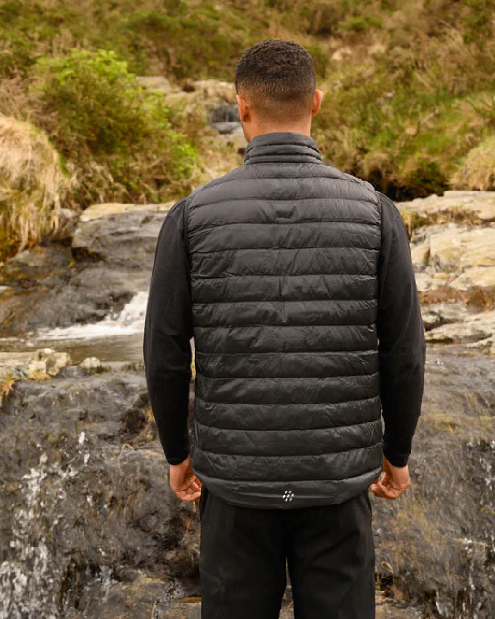 Jet Black coloured Mac In A Sac Mens Alpine Down Gilet on blurry mountain background