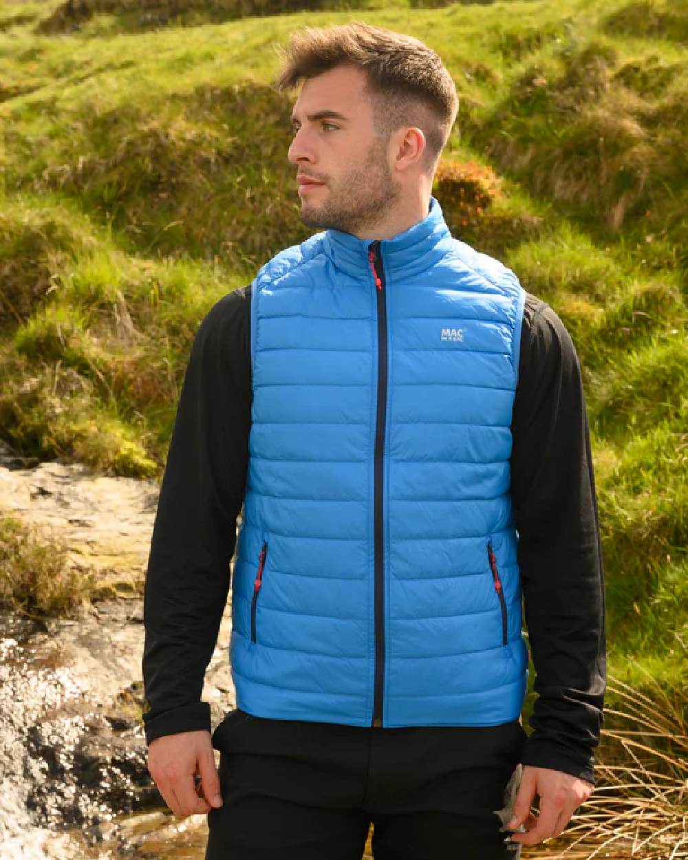 Royal coloured Mac In A Sac Mens Alpine Down Gilet on blurry green background