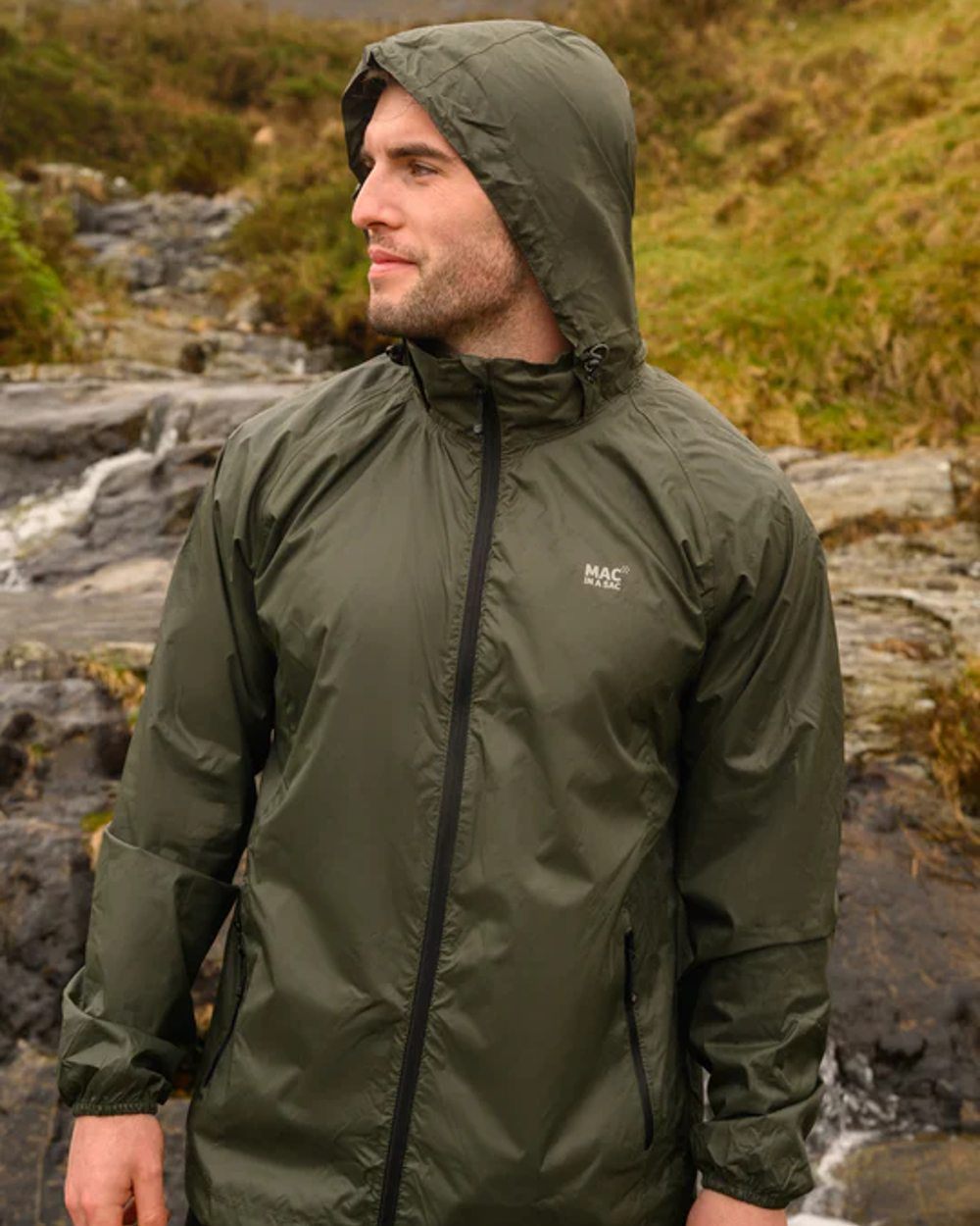 Khaki coloured Mac In A Sac Packable Origin Waterproof Jacket on outdoor background