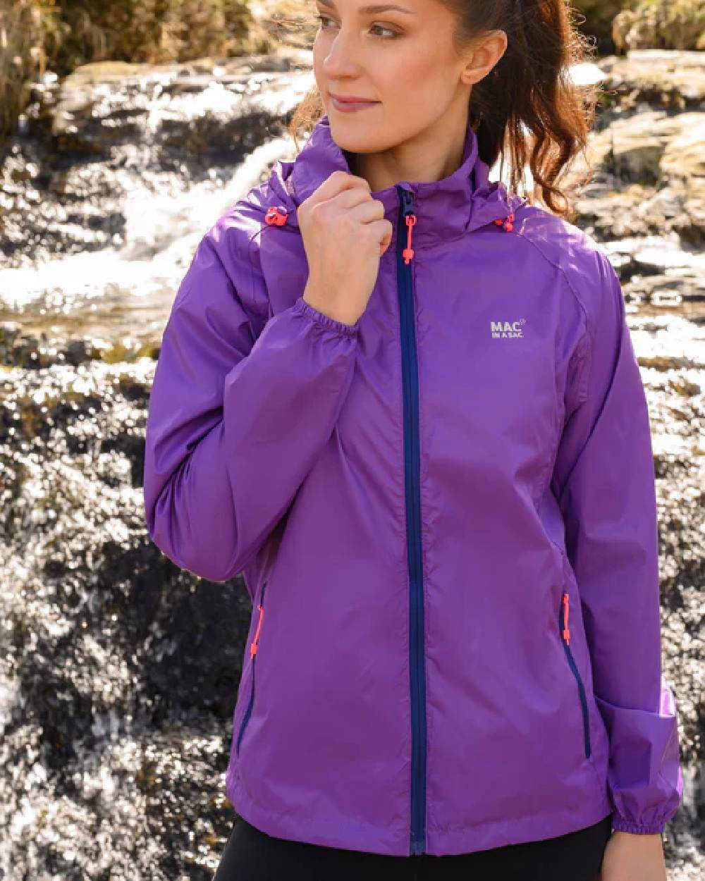 Purple coloured Mac In A Sac Packable Origin Waterproof Jacket on outdoor background