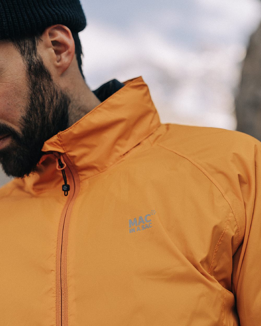Soft Orange Coloured Mac In A Sac Origin Packable Waterproof Jacket on outdoor background