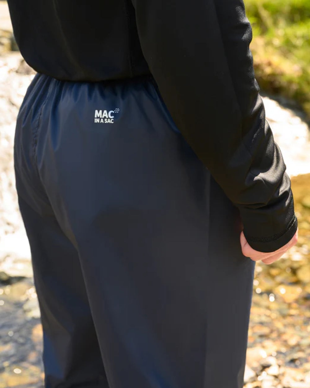Navy coloured Mac In A Sac Origin Packable Waterproof Overtrousers on blurry background