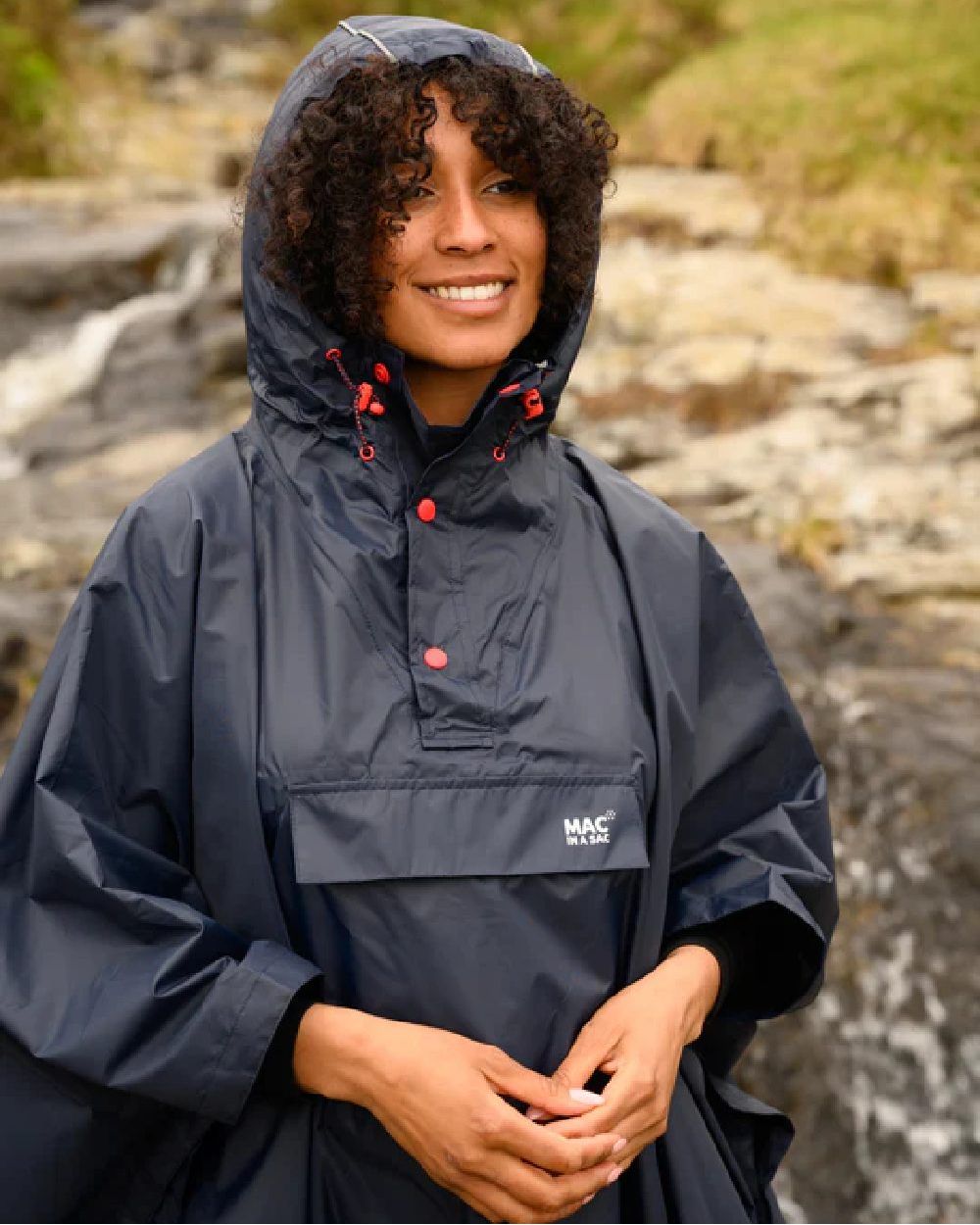 Navy Coloured Mac In A Sac Origin Waterproof Poncho on blurry background