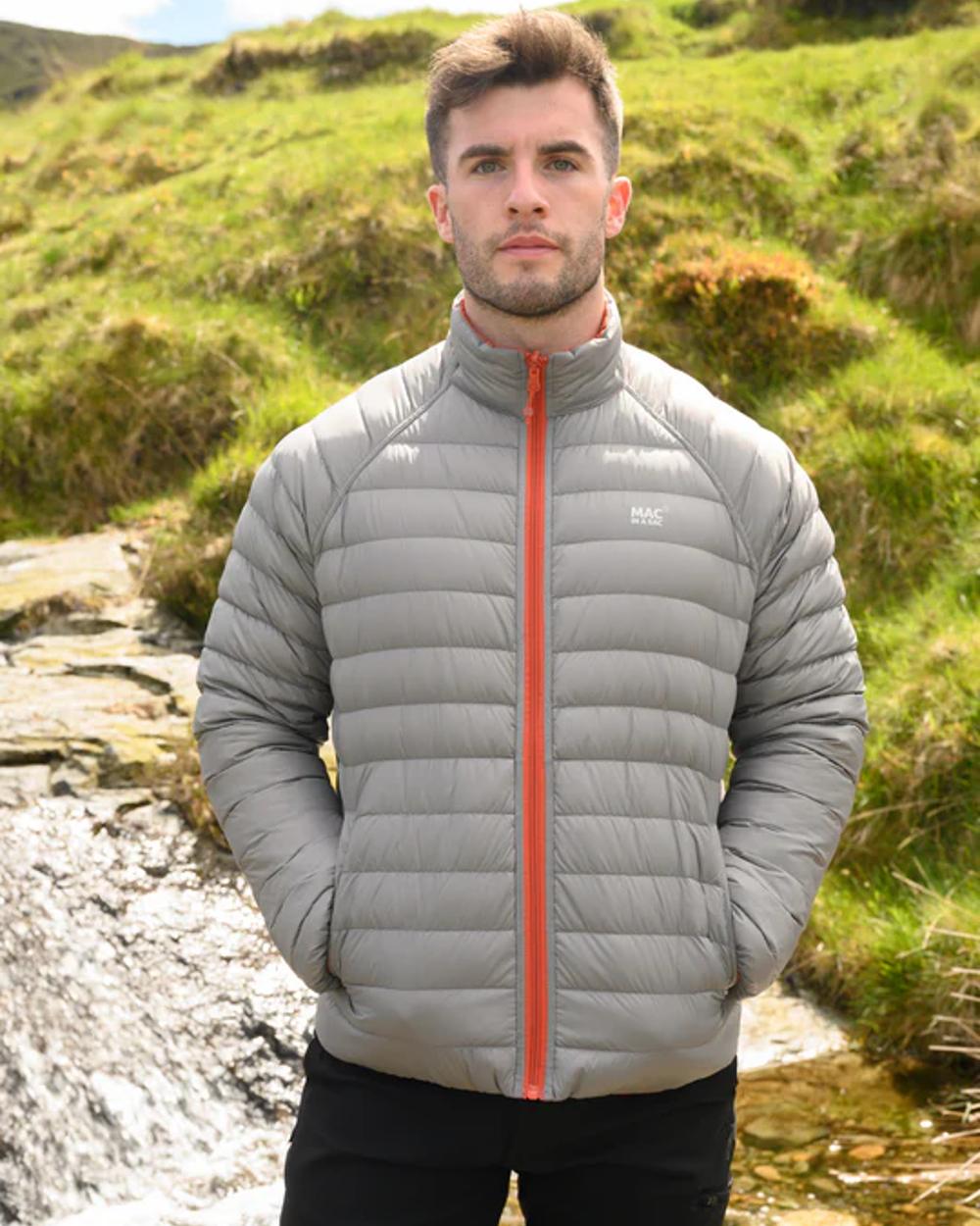 Burnt Orange Grey coloured Mac In A Sac Packable Mens Polar Down Jacket on blurry green background