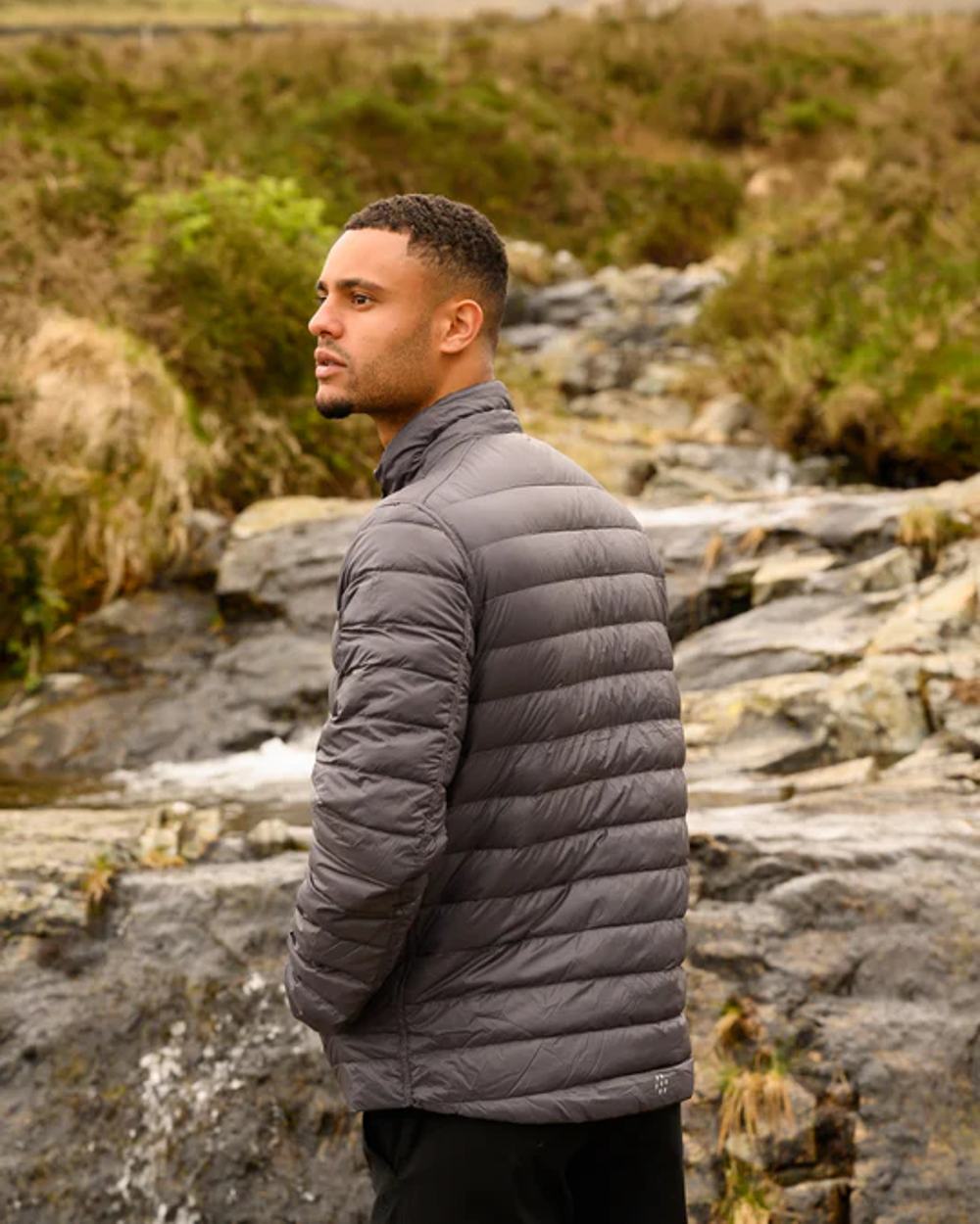 Jet Black Charcoal coloured Mac In A Sac Packable Mens Polar Down Jacket on blurry green background