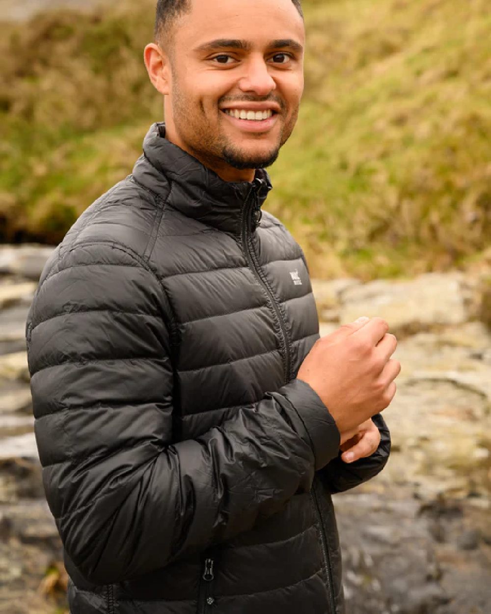 Jet Black Charcoal coloured Mac In A Sac Packable Mens Polar Down Jacket on blurry green background