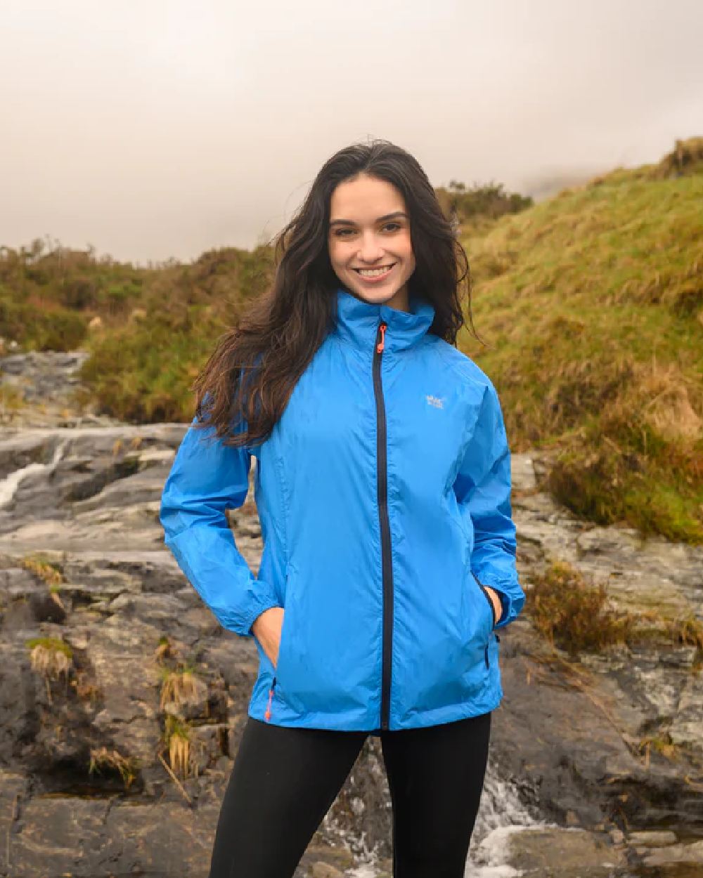 Ocean Blue coloured Mac In A Sac Packable Origin Waterproof Jacket on blurry background