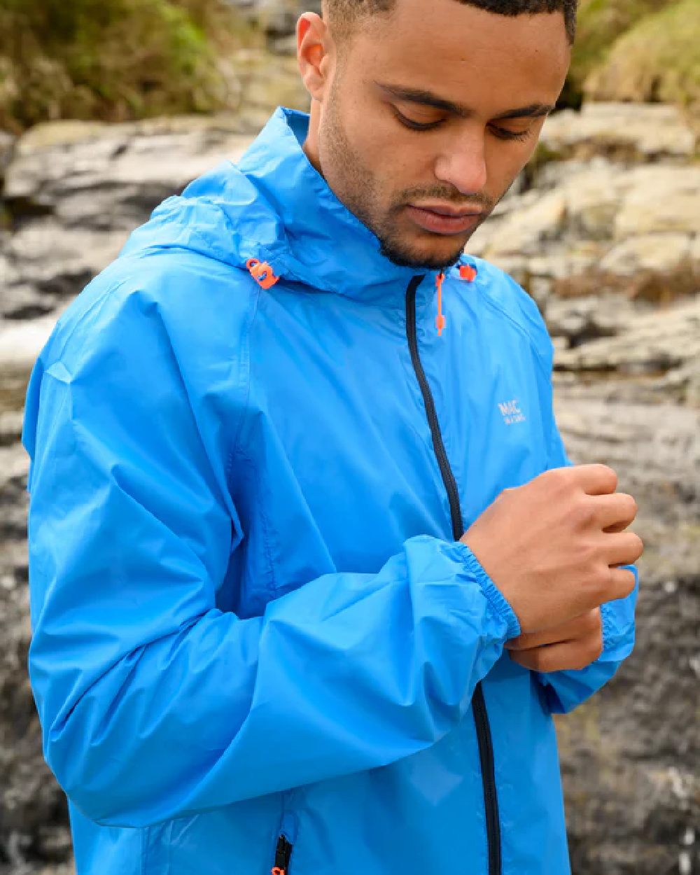 Ocean Blue coloured Mac In A Sac Packable Origin Waterproof Jacket on blurry background
