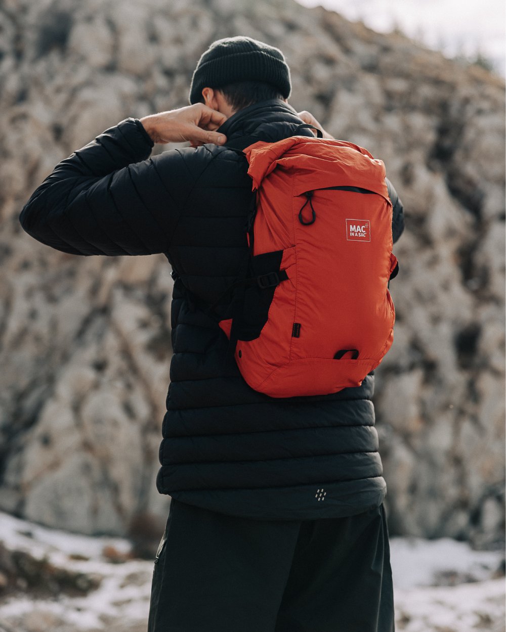 Burnt Orange coloured Mac In A Sac Travelite Packable Waterproof Backpack on forest background