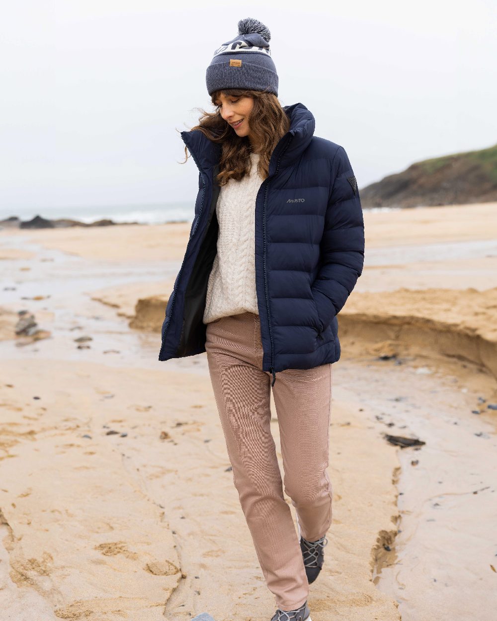 Ombre Blue Coloured Musto Bobble Hat on beach background