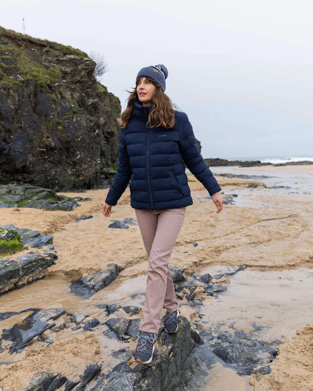 Ombre Blue Coloured Musto Bobble Hat on beach background