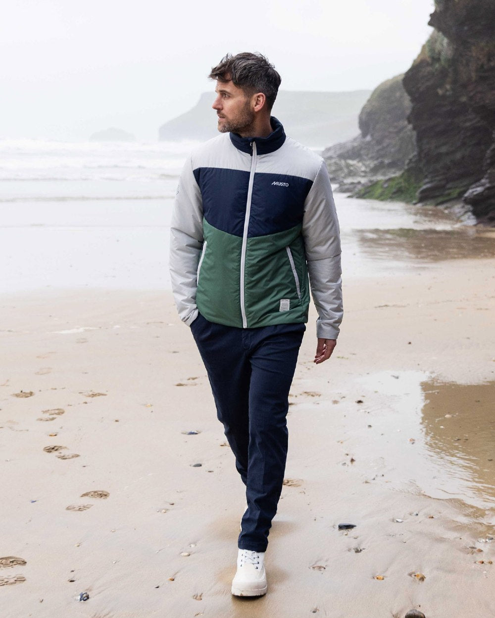 Duck Green coloured Musto Mens 64 PrimaLoft Jacket On A Beach Background