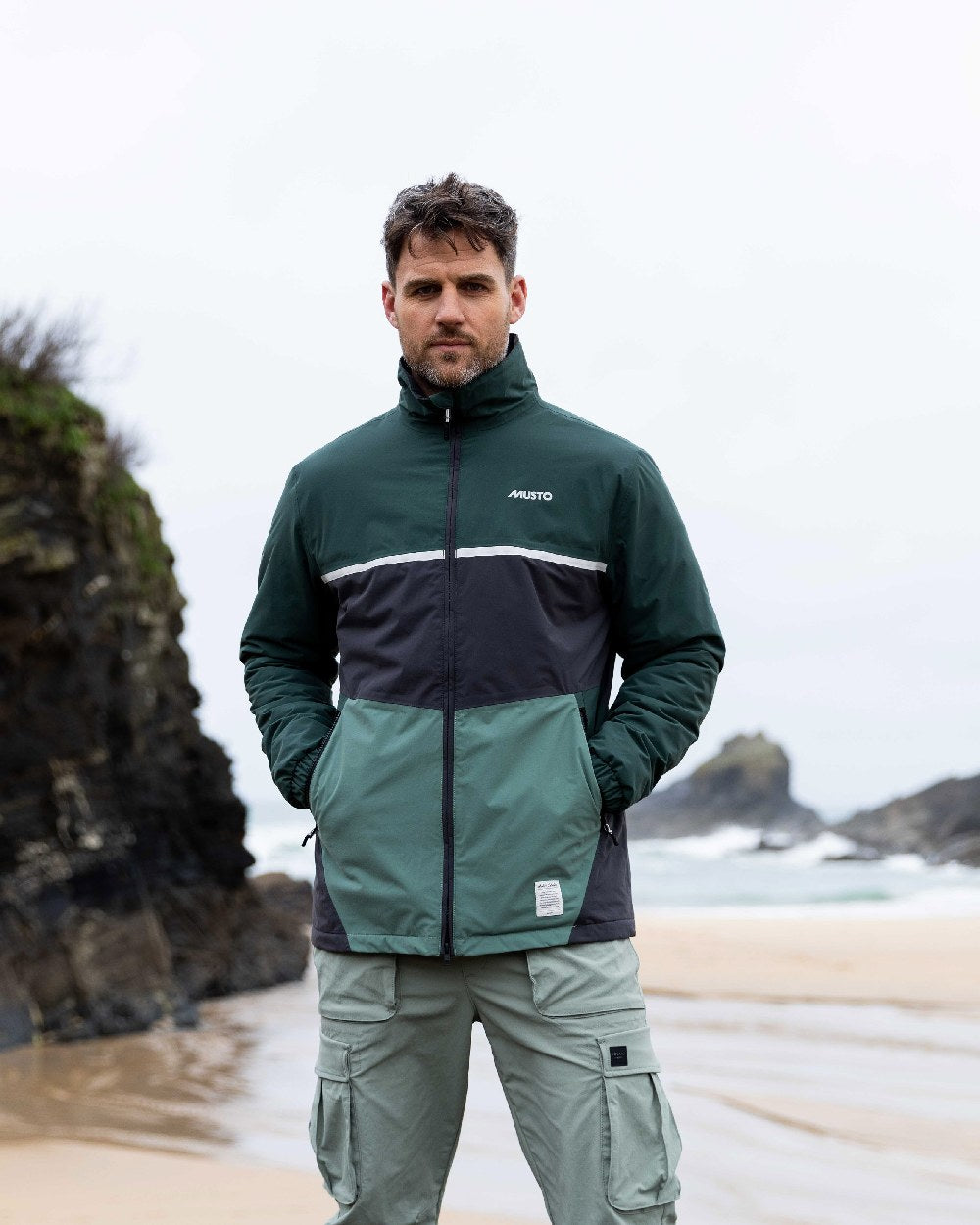 Black Darkest Spruce Coloured Musto Mens 64 Regatta Jacket on beach background