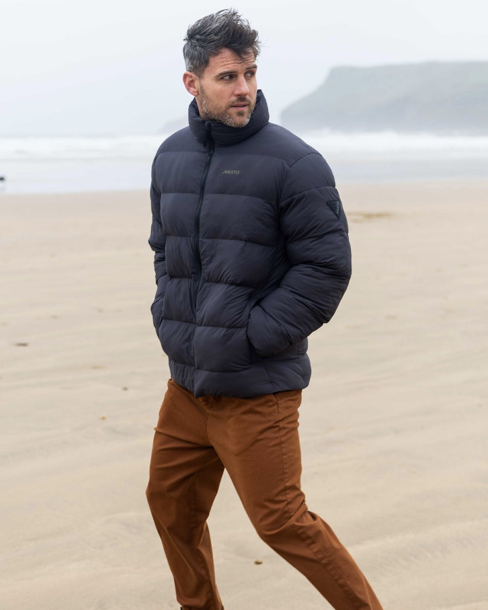 Carbon Coloured Musto Mens Active Puffer Jacket on beach background