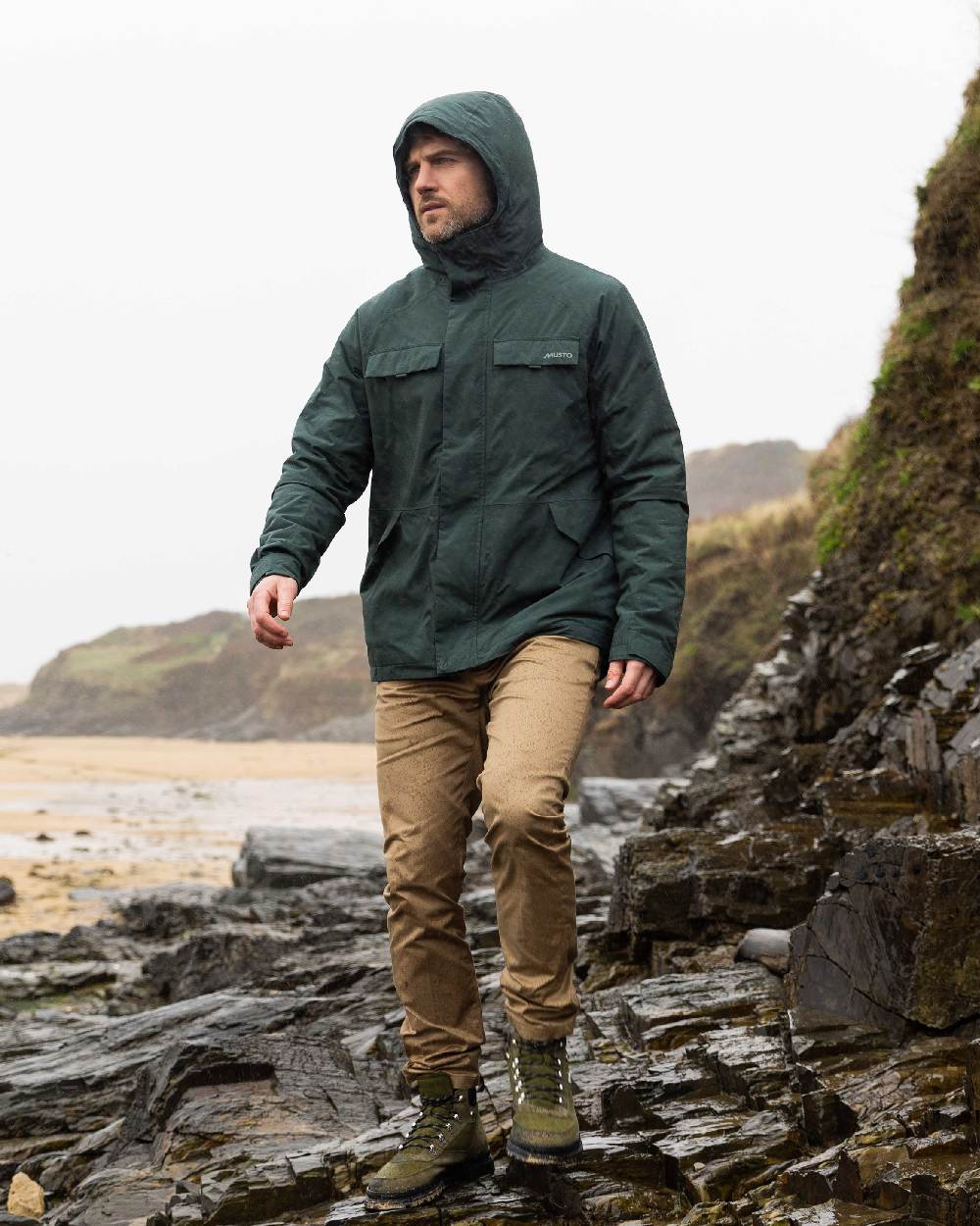 Darkest Spruce Coloured Musto Mens Insulated Rain Jacket on beach background