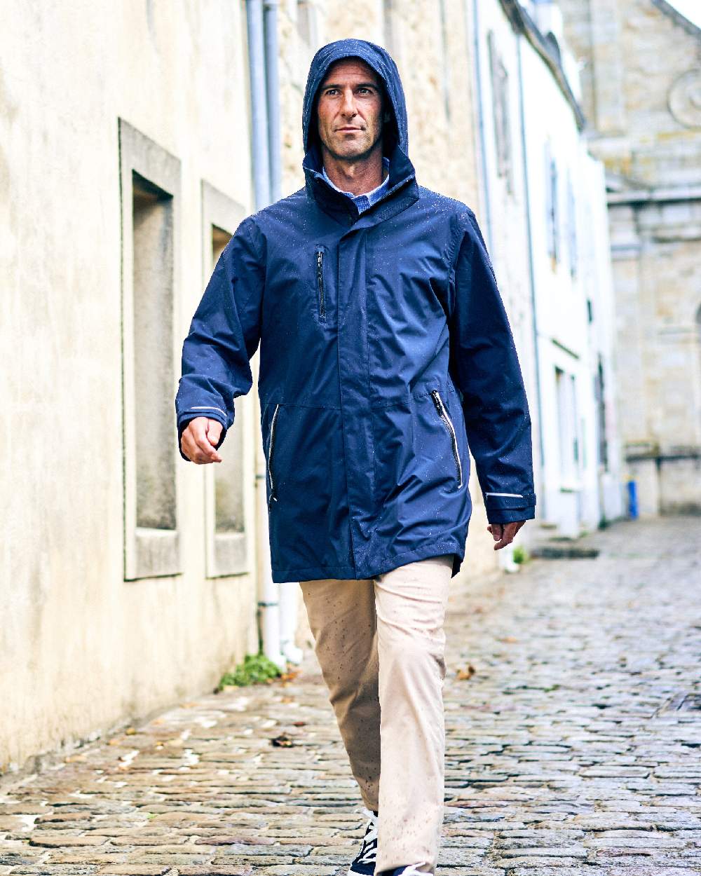 Navy coloured Musto Sardinia Long Rain Jacket on wall background