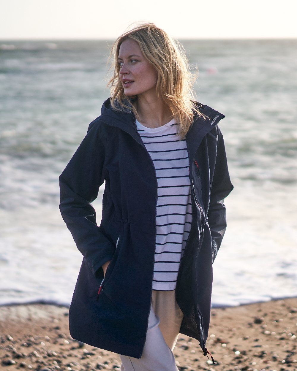 Navy coloured Musto Ladies Sardinia Rain Jacket on Beach background