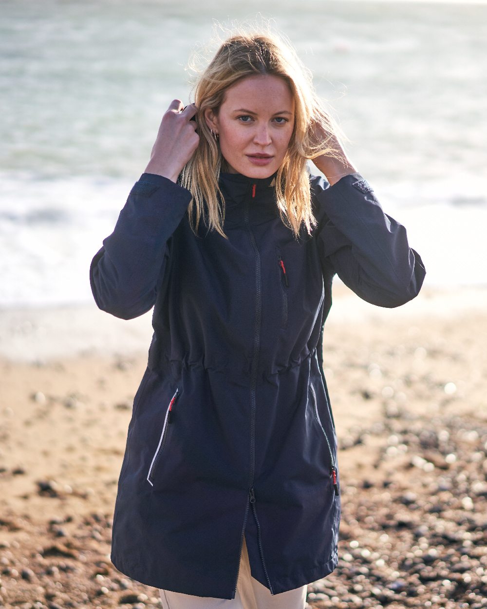 Navy coloured Musto Ladies Sardinia Rain Jacket on Beach background