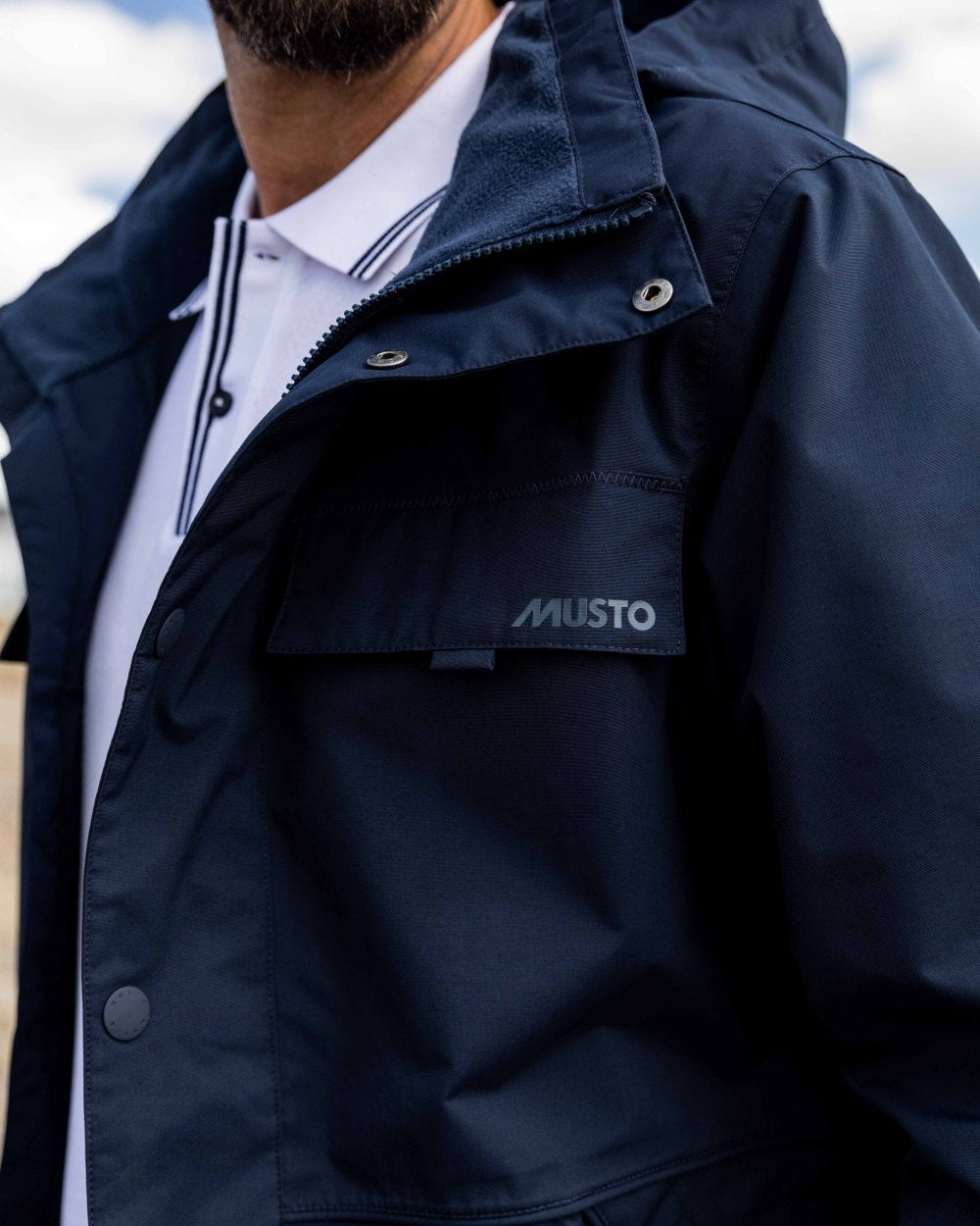 Navy Coloured Musto Mens Classic Shore Waterproof Jacket On A Beach Background 