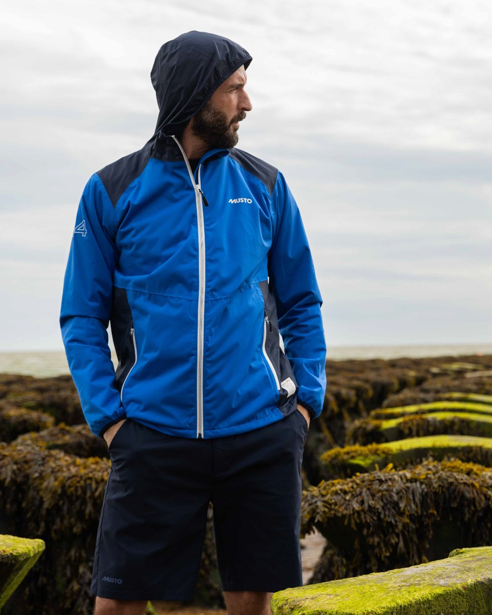 Navy Coloured Musto Mens RIB Fast Dry Shorts On A Coastal Background